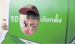  ??  ?? EAGER TO VOTE: Pheu Thai member Watana Muangsook poses with a backdrop which says ‘Waiting for the election’ as he joins the event at Thammasat University.