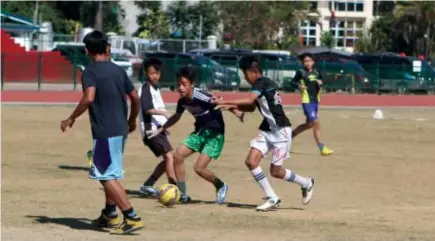  ?? Photo by Roderick Osis ?? SKIRMISH. Baguio City National High School students play a pick-up game of football at the Baguio Athletic Bowl during their free time to hone their skills.