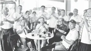  ?? ?? SEDIA BERKHIDMAT: Wong (berdiri, tujuh kiri) bersama pasukannya dan orang ramai pada kaunter perkhidmat­an bergerak SUPP Cawangan Dudong di Sibu, semalam.