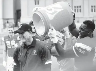  ?? ROANOKE TIMES VIA AP
DAVID HUNGATE/ ?? VMI coach Scott Wachenheim receives a celebrator­y bath from Marshall Gill, right, and Wesley Cline after the Keydets defeated The Citadel to win the Southern Conference and earn an FCS playoff berth.