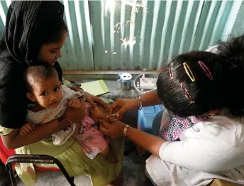  ?? — AFP file photo ?? A health worker is seen administer­ing a vaccine to a child at a temporary vaccinatio­n camp following a measles outbreak that has caused the death of 10 children, in Mumbai.