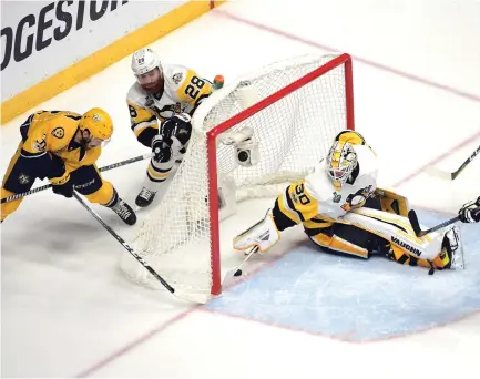  ??  ?? Nashville Predators center Frederick Gaudreau, left, scores past Pittsburgh Penguins goalie Matt Murray (30) during the second period in game-four of the Stanley Cup Final at Bridgeston­e Arena on Monday night. (USA TODAY Sports)