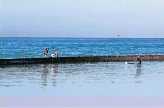  ?? | LEON LESTRADE ?? RECREATION­AL fishermen at Monwabisi Beach in the Western Cape search for bait in the tidal pool. Some of the popular spots for fishing along the province’s coast are between Monwabisi and Muizenberg. African News Agency (ANA)