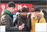  ?? ZOU HONG / CHINA DAILY ?? People check job postings at a job fair in Xihongmen, Daxing district in Beijing on Monday
