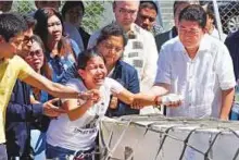  ?? AP ?? Jessica (centre) and Jojit Demafelis (left) siblings of Joanna Demafelis, react as the wooden casket with her remains arrives at the Ninoy Aquino Airport yesterday.