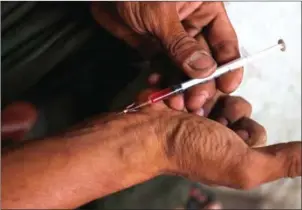  ?? HENG CHIVOAN ?? A man uses a syringe to inject drugs into his veins in Phnom Penh this week.