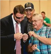  ?? Jacy Lewis / 191 News ?? Rep. Dan Crenshaw looks at World War II photos with veteran Jerry Wilkinson and his friend Charles Calloway earlier this year in Odessa.