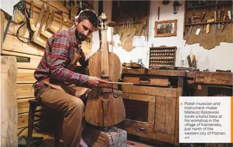  ?? AFP ?? Polish musician and instrument-maker Mateusz Raszewski tunes a kalisz bass at his workshop in the village of Kamiensko, just north of the western city of Poznan.