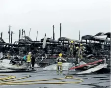  ?? MICHAEL RUBINKAM/THE ASSOCIATED PRESS ?? Firefighte­rs clear wreckage from a school bus depot in South Whitehall, Pa., that was destroyed by fire on Friday.