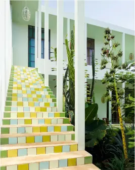  ??  ?? L’ESCALIER EXTÉRIEUR qui mène aux chambres reprend le thème des carreaux de céramique, dans des variations de vert, bleu et jaune.