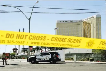  ??  ?? Crime scene tape surrounds the Mandalay Hotel (background with shooters window damaged top right).