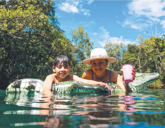  ?? Picture: CHE CHORLEY ?? Levi Wilcocks and son Chace Gilmore, 8, float on the only crocodile in the springs at Berry Springs Nature Park