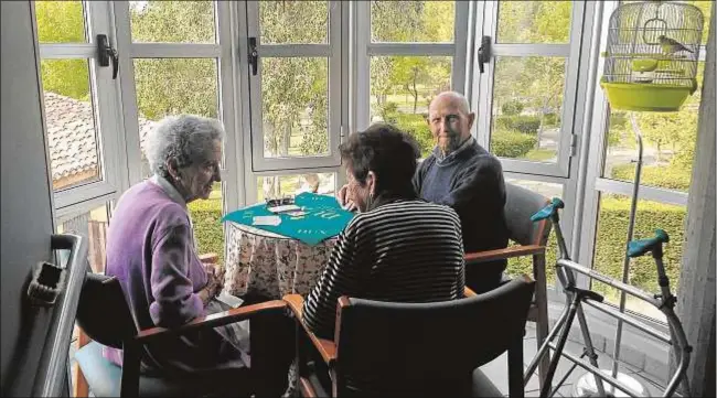  ?? Fotos: Centro Asistencia­l San Roque ?? Un grupo de residentes del centro San Roque juega a las cartas. A la derecha, una anciana elabora, en compañía de su familia y el persona, su historia y proyecto de vida