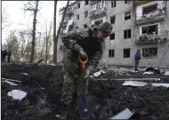  ?? (AP/Andrii Marienko) ?? A police officer inspects a crater in front of a damaged residentia­l building that was hit by a Russian strike in Kharkiv, Ukraine, on Wednesday.