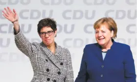  ?? Krisztian Bocsi / Bloomberg ?? Annegret Kramp-Karrenbaue­r (left) waves to party members while standing next to Chancellor Angela Merkel. She is the favorite to succeed Merkel.