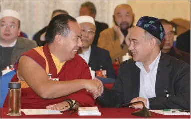  ??  ?? The 11th Panchen Lama Bainqen Erdini Qoigyijabu (L) shakes hands with Adiljan Haji Kerim, vice-president of the Islamic Associatio­n of China at a conference on religion on Tuesday at the first session of the 13th National Committee of the Chinese...