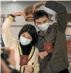  ?? GETTY IMAGES ?? A couple pose while getting their marriage certificat­e on Wednesday in Wuhan. Figures for the death toll in the city have been revised as the area has lifted restrictio­ns in some areas for residents.