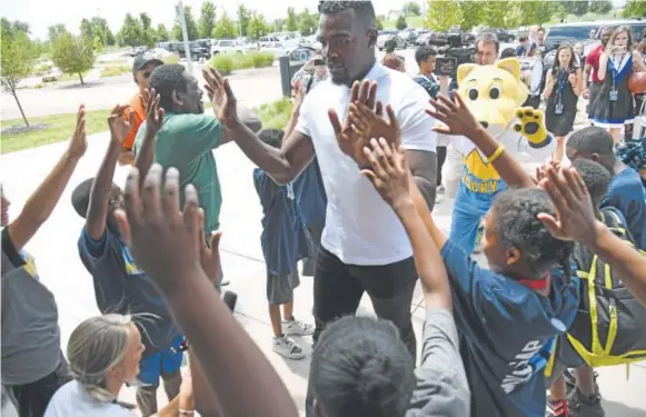  ??  ?? NBA all-star forward Paul Millsap high-fives children Thursday at the Montbello Recreation Center, only 2 miles from his neighborho­od as a youth.