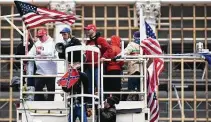  ?? Astrid Riecken / Washington Post ?? A rioter holds up a Confederat­e flag after scaling a scaffoldin­g at the U.S. Capitol in support of President Donald Trump.