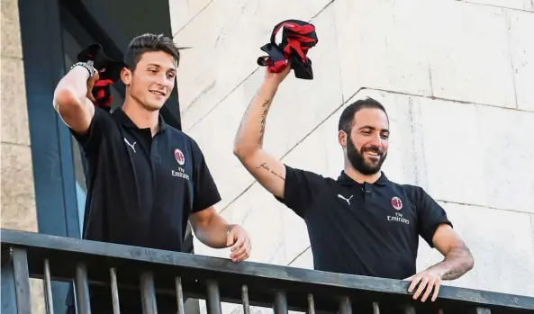  ?? — AFP ?? Grand welcome: Gonzalo Higuain (right) and Mattia Caldara throwing AC Milan jerseys to fans from a balcony in Milan’s central Piazza Duomo square on Friday.