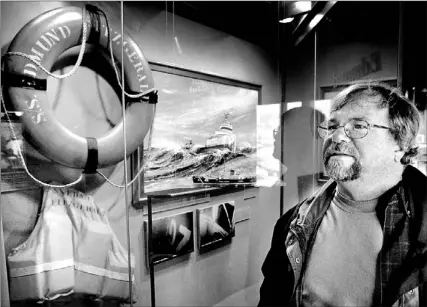  ?? JIM MONE/ AP PHOTO ?? Dan Christians­on, a Wisconsin teacher who lost a friend on board, gazes at Edmund Fitzgerald life ring and safety vest on display at the Lake Superior Maritime Museum in Duluth, Minn. Today marks 30 years since the Great Lakes sinking.