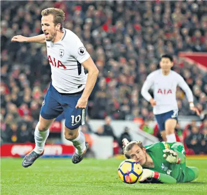  ??  ?? Fall guy: Harry Kane goes down after being clipped by Loris Karius at Anfield on Sunday (above) and wearing an Arsenal shirt as a boy (below, left)