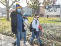  ??  ?? A woman leaves the Scarboroug­h elementary school after taking her two children out after hearing of the outbreak.