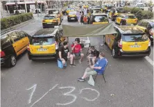  ?? AP PHOTOs ?? HACKED OFF: Taxi drivers, above, block the Gran Via avenue in Barcelona, Spain, yesterday to protest the use of ride-hailing apps like Uber and Cabify. Top right, a man takes a photograph of parked taxis blocking the main Castellana avenue in Madrid.