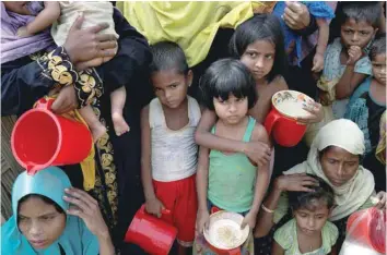  ?? — Reuters ?? Rohingya women and children wait to get distribute­d meals at refugee settlement near Cox’s Bazar, Bangladesh.