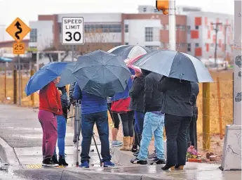  ?? JIM THOMPSON/JOURNAL ?? Parents and family members of students wait under umbrellas at the entrance to Rio Grande High School Thursday morning while the school was locked down.