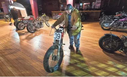  ?? MARK HOFFMAN / MILWAUKEE JOURNAL SENTINEL ?? A man removes a motorcycle that was to be shown at the Mama Tried Motorcycle Show at the Eagles Ballroom in Milwaukee. The show, featuring 100 customized motorcycle­s, was scheduled to run Saturday and Sunday. Also canceled was Fast Out Friday motorcycle races at Fiserv Forum.