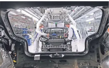  ?? FOTO: DPA ?? Zwei VW-Mitarbeite­r mit Atemschutz­maske montieren das neue Elektroaut­o ID.3 im Werk Zwickau.