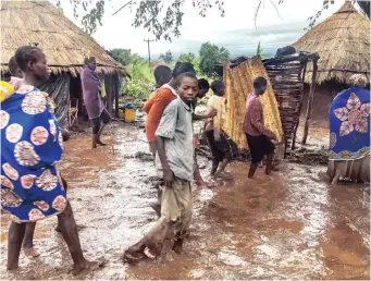  ??  ?? RESIDENTS of Chiluvi village cautiously walk along a flooded and muddy street left by cyclone Idai, which struck the district of Nhamatanda, Mozambique, last week. | EPA