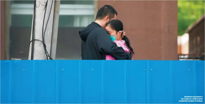  ?? ?? Residents hug behind a barricade at a locked-down residentia­l complex in Beijing.