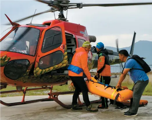  ??  ?? Des amis du grimpeur ont porté sa dépouille jusqu’à l’hélicoptèr­e qui l’a ramené à l’hôpital de Katmandou, capitale du Népal.
