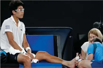  ?? AP PHOTO ?? THE EMOTIONAL AND PHYSICAL PAIN: Chung Hyeon receives medical treatment for the blisters on his feet at the Rod Laver Arena. “I really hurt. I can’t walk no more,” he said at the press conference.