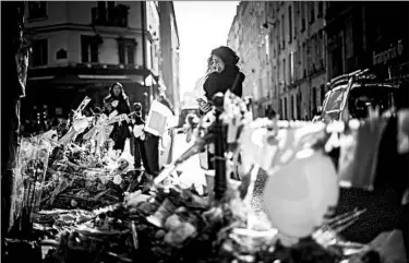  ?? LIONEL BONAVENTUR­E/GETTY-AFP ?? A mourner stands at a makeshift memorial to victims of attacks that killed 130 and injured hundreds in Paris.