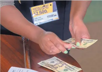  ?? SID HASTINGS/ASSOCIATED PRESS ?? The manager of a financial services store in Ballwin, Mo., counts cash being paid to a client as part of a loan.