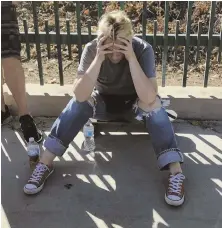  ?? AP PHOTO ?? SHAKEN: An unidentifi­ed woman sits next to witnesses on a sidewalk after a gunman barricaded himself inside a Trader Joe’s store in Los Angeles.