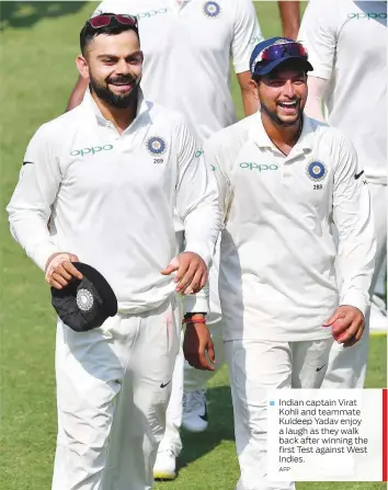  ?? AFP ?? Indian captain Virat Kohli and teammate Kuldeep Yadav enjoy a laugh as they walk back after winning the first Test against West Indies.