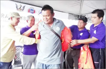  ??  ?? (From left) Abdullah, Murni, Richard (second right) and Leonard help a fisherman put on a life jacket.