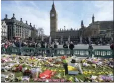  ?? JOHN STILLWELL — PA VIA AP ?? People look at tributes in Parliament Square, London, Saturday laid out for the victims of the Westminste­r attack on Wednesday. Khalid Masood killed four people and left more than two dozen hospitaliz­ed, including some with what have been described as catastroph­ic injuries. The Islamic State group claimed responsibi­lity for the attack.