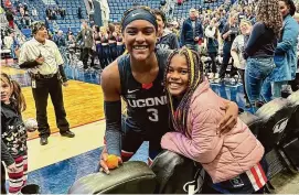  ?? Mickey Grace/Contribute­d photo ?? UConn women’s basketball forward Aaliyah Edwards poses with Aria Grace after a game at the XL Center. Aria wears purple and gold braids because of Edwards.