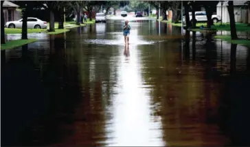  ?? BRENDAN SMIALOWSKI/AFP ?? A woman walks down a flooded road during the aftermath of Hurricane Harvey on Wednesday in Houston.