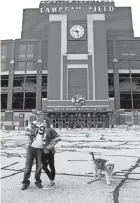  ?? SARAH KLOEPPING/USA TODAY NETWORK-WISCONSIN ?? Ben Lawrence and Jenna Benson pose for a photo with their dogs outside Lambeau Field before the Packers home opener against the Lions on Sunday. Fans were not allowed to attend the game due to the coronaviru­s pandemic.