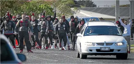  ??  ?? Mongrel Mob members perform a rousing haka as Kevin Ratana’s body is removed from the scene. Below, a Mongrel Mob member looks across at the house where the shooting took place.