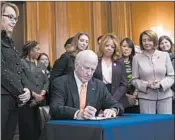  ?? ALEX BRANDON/AP ?? Former Rep. Gabby Giffords, left, watches as Democratic Rep. Mike Thompson signs a gun control bill Tuesday in Washington. Giffords was shot in the head eight years ago.