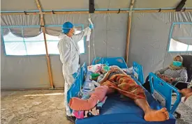  ?? (AFP) ?? A nurse attends a patient injured in Friday’s earthquake at a makeshift ward outside West Sulawesi General Hospital due to concerns of aftershock­s, in Mamuju on Monday