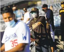  ??  ?? Dodgers fan Will Gutierrez and Padres fan Maurcio Esquer watch batting practice before Friday’s game between the two teams.