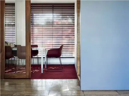  ??  ?? Above — Subtly offsetting the maroon backdrop, soft blue hues add a sophistica­ted complexity to the overall office palette.